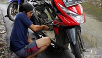 Warga saling bantu memperbaiki motor yang terendam banjir di kawasan Rawa Terate, Jakarta.