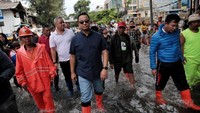 Memakai boots, Anies Baswedan berjalan di tengah genangan air. 