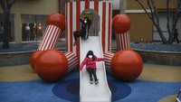 Dua orang anak asyik bermain perosotan di salah satu taman bermain yang berada di area pusat perbelanjaan Beijing, China. Keduanya juga tampak mengenakan masker saat bermain di luar ruangan tersebut. Getty Images/Kevin Frayer.