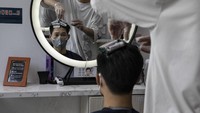 Seorang warga mengenakan masker saat sedang menata rambutnya di salah satu salon di kawasan pecinan yang berada di Phnom Penh, Kamboja. Getty Images/Paula Bronstein.