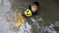 Seorang anak asyik bermain banjir tanpa menghiraukan dampaknya.