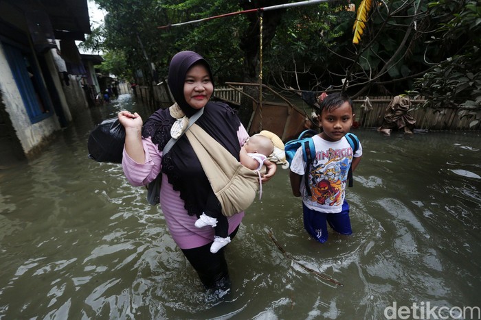 Banjir di Rawa Terate Cakung Warga melintasi banjir di RT 10 RW 05 Kelurahan Rawa Terate, Cakung, Jakarta Timur, Senin (24/2/2020). Banjir dikawasan ini sudah melanda sejak minggu 23 Februari hingga kini belum surut. Kemarin ketinggian air mencapai 2,5 m dan hari ini masih mencapai 60 cm. Menurut salah satu warga Sri Aminah hingga hari ini mereka belum mendapat bantuan dan mereka membutuhkan air bersih dan makanan. listrik dikawasan ini pun padam.