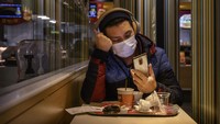 Seorang warga mengenakan masker usai menghabiskan makan malam di salah satu restoran cepat saji yang berada di Beijing, China. Getty Images/Kevin Frayer.