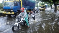 Polisi membantu pengendara mendorong motornya yang mogok akibat banjir di Jalur Pantura Pekalongan, Jawa Tengah.