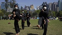 Sejumlah warga Indonesia sedang berlatih seni bela diri di kawasan Victoria Park, Hong Kong. Mereka tampak mengenakan masker saat berlatih bela diri di luar ruangan guna mencegah terinfeksi virus corona. AP Photo/Kin Cheung.