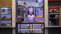 Seorang koki di Beijing, China, tampak menunggu pembeli untuk berbelanja berbagai kue yang dijajakan di toko kue tersebut. AP Photo/Ng Han Guan.
