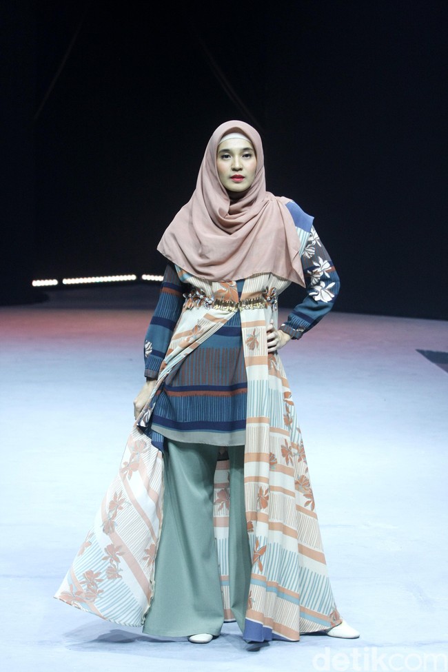 Dhini Aminarti membuka fashion show persembahan Wardah di MUFFEST 2020 dengan berjalan di catwalk sebagai model busana muslimah karya brand KAMI. Dhini tampil dengan lipstik bold berwarna merah saat memeragakan busana KAMI yang dihiasi bunga melati. Foto: Mohammad Abduh/Detikcom
