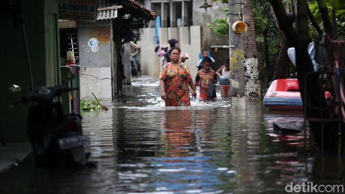 Warga melintasi banjir di RT 10 RW 05 Kelurahan Rawa Terate, Cakung, Jakarta Timur, Senin (24/2/2020). Banjir dikawasan ini sudah melanda sejak minggu 23 Februari hingga kini belum surut. Kemarin ketinggian air mencapai 2,5 m dan hari ini masih mencapai 60 cm. Menurut salah satu warga Sri Aminah hingga hari ini mereka belum mendapat bantuan dan mereka membutuhkan air bersih dan makanan. listrik dikawasan ini pun padam.