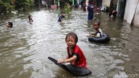 Anak-anak justru menjadikan genangan banjir sebagai arena bermain.