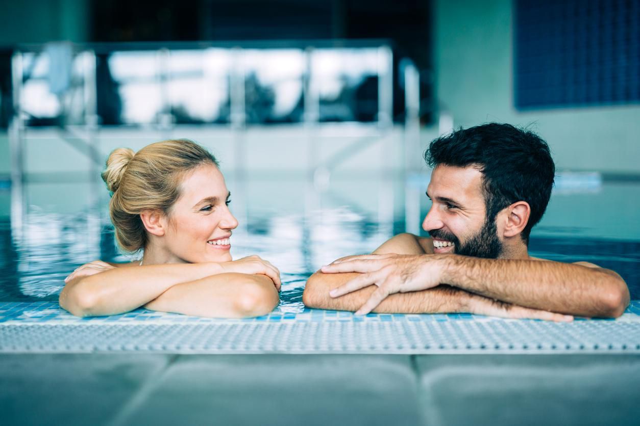 Happy attractive couple relaxing in spa swimming pool