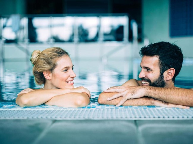 Happy attractive couple relaxing in spa swimming pool