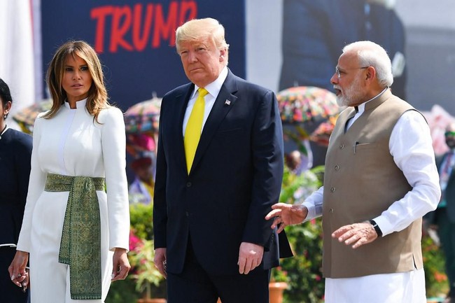 Melania Trump tampak memakai jumpsuit putih formal berpotongan maskulin yang terinspirasi dari kostum tradisional pria India. Kerah dan siluet atasannya seperti jas tutup yang umum di Indonesia. Celana berpotongan flare menjaga penampilan ibu satu anak itu tetap elegan. (Foto: Mandel NGAN / AFP)