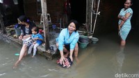 Warga harus mencuci pakaian menggunakan genangan banjir karena kekurangan air bersih.