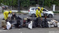 Seorang petugas tampak meletakkan material aspal di atas jalan yang berlubang di kawasan Jalan Kwini II, Jakarta Pusa. Ada pula seorang petugas yang sedang meratakan material aspal di atas jalan tersebut.