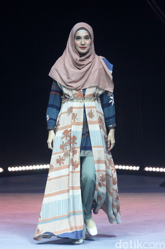 Dhini Aminarti tampil dengan gaya hijab khasnya yang syari. Dhini berjalan di catwalk dengan gaya busana tumpuk khas hijabers yaitu memakai tunik yang dipadukan dengan celana panjang dan outer. Foto: Mohammad Abduh/Detikcom
