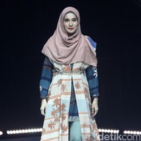 Dhini Aminarti tampil dengan gaya hijab khasnya yang syari. Dhini berjalan di catwalk dengan gaya busana tumpuk khas hijabers yaitu memakai tunik yang dipadukan dengan celana panjang dan outer. Foto: Mohammad Abduh/Detikcom