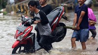 Sebagian pengendara mengangkat bagian belakang motor saat melintasi banjir. Aksi itu dilakukan agar motornya tidak mogok.