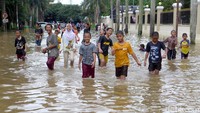 Sejumlah anak tampak asyik bermain air di kawasan perumahan Cipinang Indah, Jakarta, yang terendam banjir, Selasa (25/2/2020).