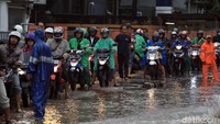 Tampak sejumlah pengendara motor juga mengenakan jas hujan agar tidak basah saat melintasi jalan yang banjir tersebut.