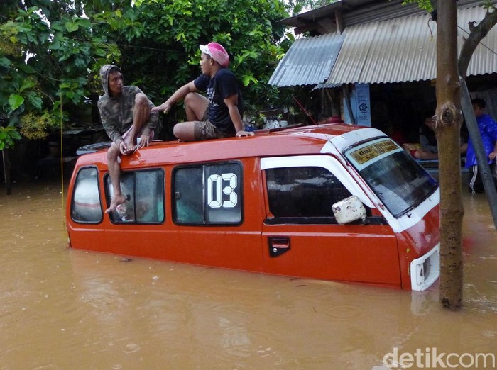 Sejumlah warga melintasi banjir di RT 2 RW 3 Rawadas, Pondok Kopi, Jakarta Timur, Selasa (25/2/2020). Banjir yang melanda kawasan ini mencapai 90 meter.