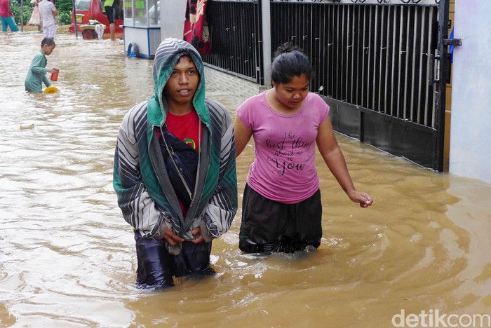 Sejumlah warga melintasi banjir di RT 2 RW 3 Rawadas, Pondok Kopi, Jakarta Timur, Selasa (25/2/2020). Banjir yang melanda kawasan ini mencapai 90 meter.