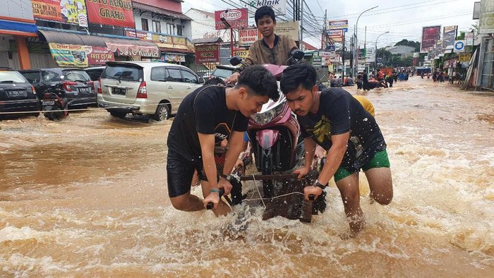 Warga Bekasi Mengais Rezeki dengan Angkut Motor di Tengah Banjir