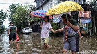 Sejumlah warga tampak beraktivitas di tengah banjir yang merendam kawasan Semper Barat, Cilincing, Jakarta Utara, Selasa (25/2/2020).