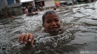 Tak hanya di dalam rumah, ada pula anak-anak yang bermain air dan berenang di tengah banjir yang merendam kawasan Semper Barat, Jakarta Utara.