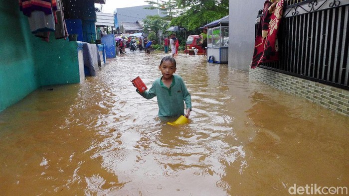 Sejumlah warga melintasi banjir di RT 2 RW 3 Rawadas, Pondok Kopi, Jakarta Timur, Selasa (25/2/2020). Banjir yang melanda kawasan ini mencapai 90 meter.