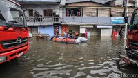 Sejumlah anak bermain di atas perahu karet saat petugas pemadam kebakaran melakukan penyedotan air.