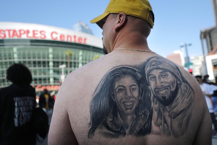 LOS ANGELES, CALIFORNIA - FEBRUARY 24: Fans gather while watching a live broadcast of the ‘Celebration of Life for Kobe and Gianna Bryant’ memorial service on a fan's iPad outside the Staples Center on February 24, 2020 in Los Angeles, California. Some fans were upset that the Staples Center didn't broadcast the event on television screens outside for those who didn't have tickets. Los Angeles Lakers NBA star Kobe Bryant, 41, and his 13-year-old daughter Gianna were killed along with seven others in a helicopter crash near Los Angeles on January 26. (Photo by Mario Tama/Getty Images)