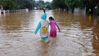 Dua orang anak nekat melintasi jalanan yang terendam banjir.