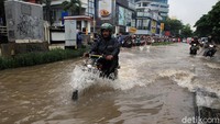 Seorang pemotor menerobos jalan yang terendam banjir di kawasan Kebon Jeruk, Jakarta.