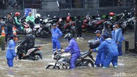 Petugas Dinas Sumber Daya Air terlihat membantu warga menerobos banjir.