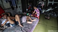 Dua orang warga tampak berbaring di atas kasur meski bagian dalam rumah mereka tergenang air.