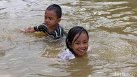 Momen banjir tersebut dimanfaatkan anak-anak untuk bermain air dan berenang bersama teman-teman.