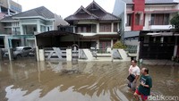 Dua orang warga tampak beraktivitas di kawasan perumahan Taman Villa Baru yang terendam banjir.