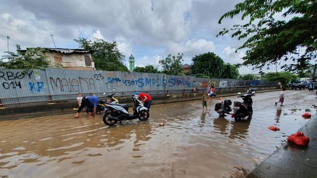 Saat Warga Bekasi Memanfaatkan Air Banjir untuk Cuci Motor