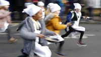 Sejumlah anak sekolah di Olney, Buckinghamshire, Inggris, ikut serta dalam lomba balap lari sambil membawa pancake, Selasa (25/2) waktu setempat.