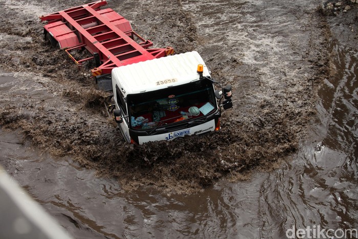 Begini aksi nekat para sopir truk saat melibas banjir di kawasan Cilincing, Jakarta Utara, Rabu (26/2). Banjir yang cukup tinggi tersebut tak menurunkan niat sopir untuk melintas.