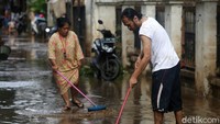 Beberapa warga tampak mendorong lumpur sisa banjir yang masuk ke halaman rumah.