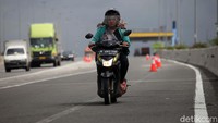 Aksi pemotor wanita melintasi jalan tol.