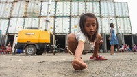 Seorang anak bermain di depan kontainer tempat mereka tinggal dan mengungsi saat banjir melanda.
