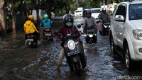 Genangan sedikit menyulitkan pengendara sepeda motor melintas.