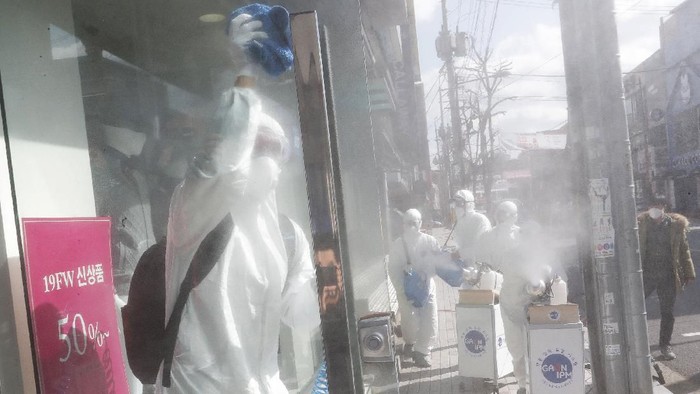 Workers wearing protective gears spray disinfectant as a precaution against the coronavirus at a shopping street in Seoul, South Korea, Thursday, Feb. 27, 2020. The new illness persists in the worst-hit areas and spreads beyond borders. (AP Photo/Ahn Young-joon)
