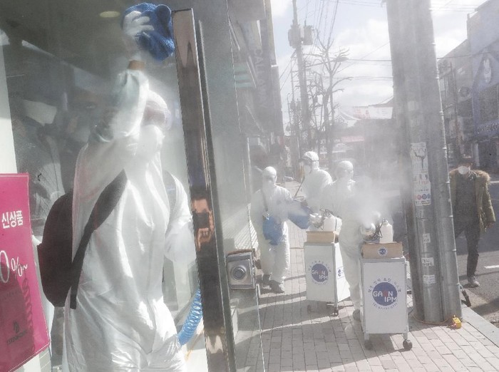 Workers wearing protective gears spray disinfectant as a precaution against the coronavirus at a shopping street in Seoul, South Korea, Thursday, Feb. 27, 2020. The new illness persists in the worst-hit areas and spreads beyond borders. (AP Photo/Ahn Young-joon)