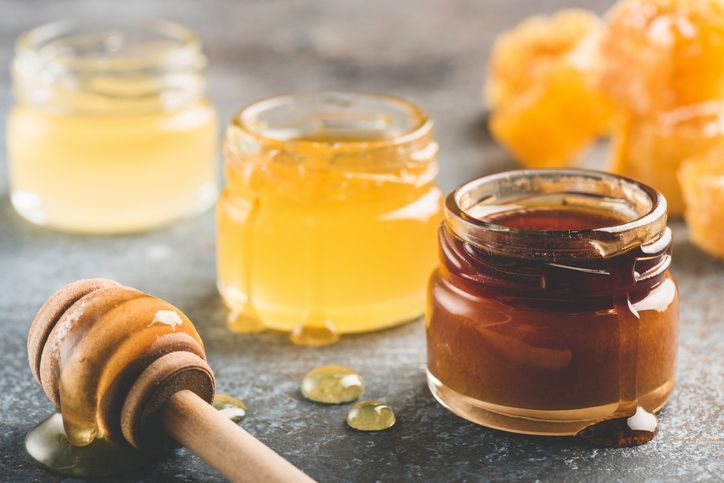 High resolution image of organic forest honey in a glass bowl with wooden honey dipper shot in studio on white background