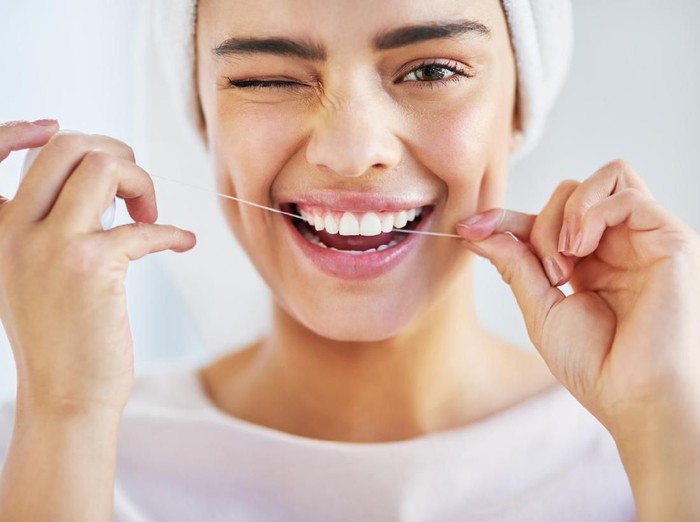 benang gigi Portrait of a beautiful young woman flossing her teeth in the bathroom at home
