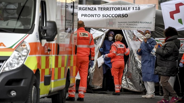 Paramedics stand next to a tent set up by the Italian Civil Protection outside the emergency ward of the Piacenza hospital, northern Italy, Thursday, Feb. 27, 2020. Italy is changing how it reports coronavirus cases and who will get tested in ways that could lower the countrys caseload even as an outbreak centered in northern Italy spreads in Europe. (Claudio Furlan/Lapresse via AP)