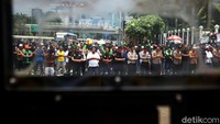 Polisi bersama massa pengemudi ojek online (Ojol) yang telah melakukan aksi unjuk rasa melaksanakan salat Jumat berjamaah di depan Gedung DPR, Jakarta, Jumat (28/2/2020).